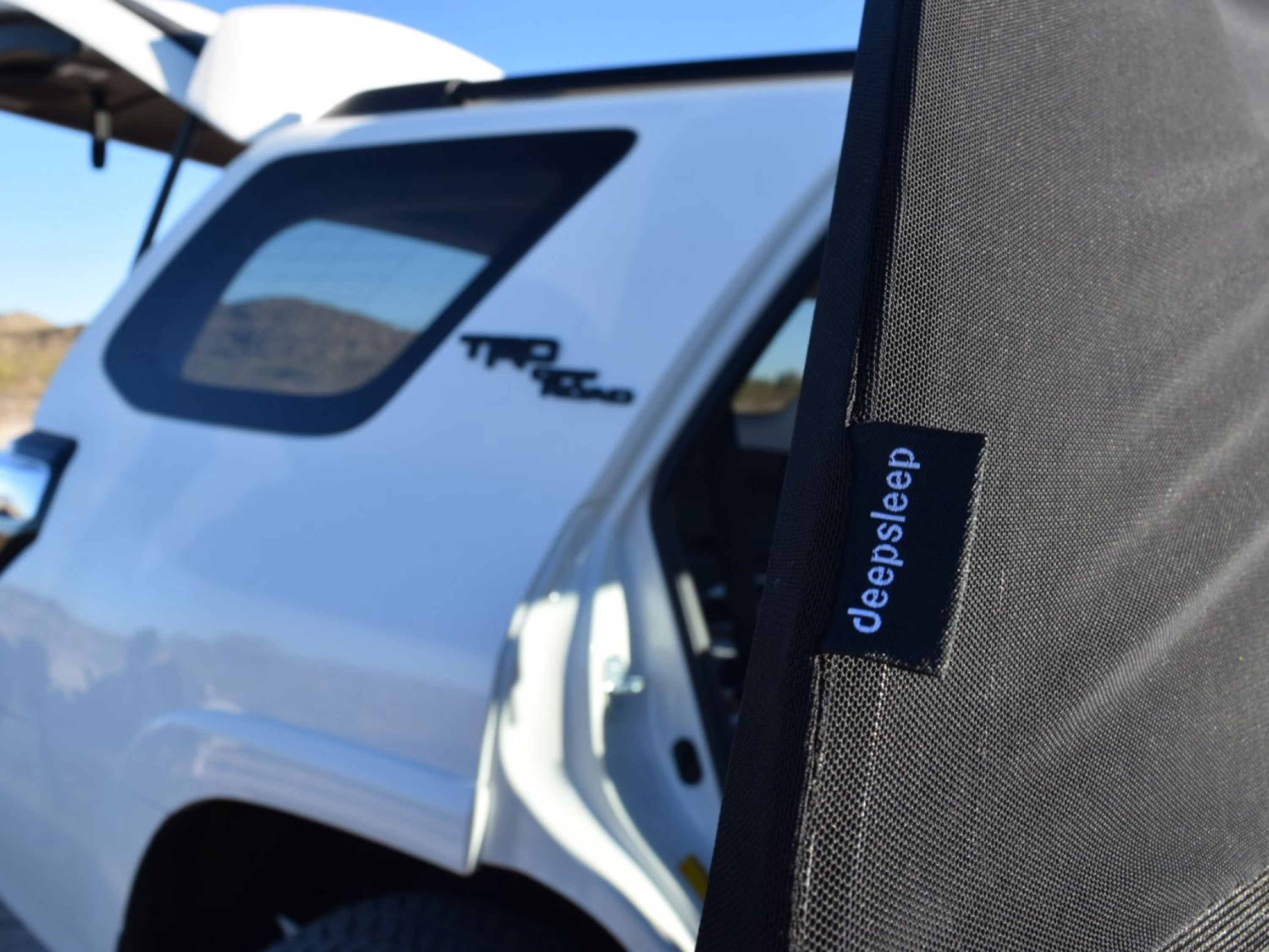 Closeup of Deepsleep car camping mesh window screen on back passenger window of white Toyota 4-Runner