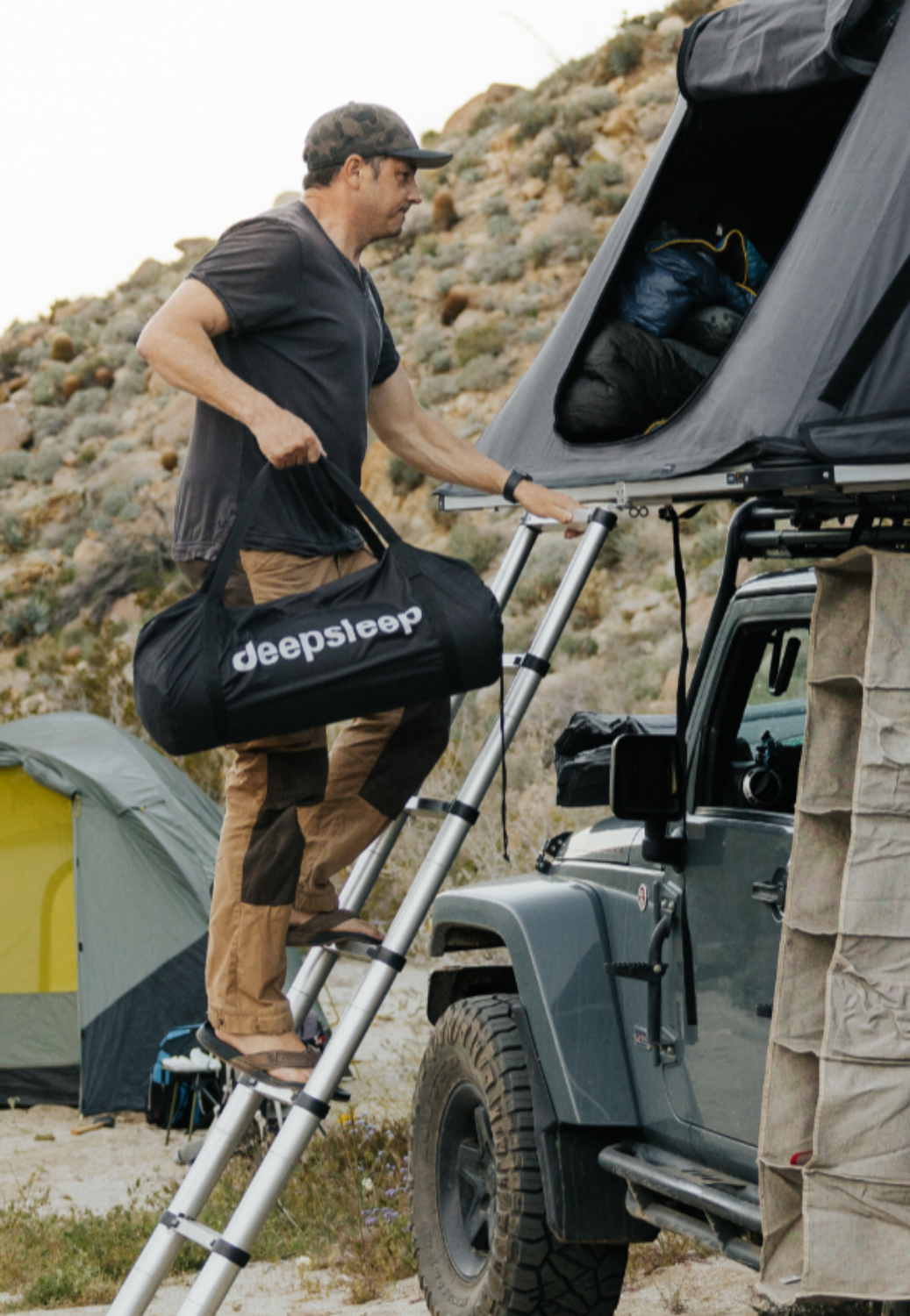 man carrying deepsleep camping mat into rooftop tent